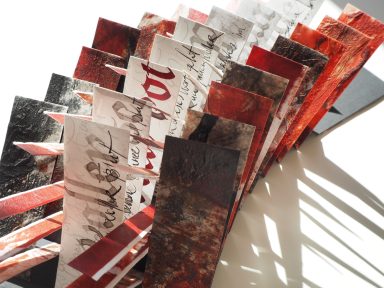 Unikatbuch mit Fahnenbuch-Bindung. Dynamische Papierstreifen in rot, schwarz und zusätzlich kalligrafisch gestaltet. 